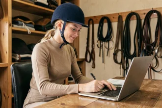 Cavalière débutante qui remplit son inscription sur le site SIF FFE depuis un bureau en salle de sellerie