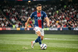 Joueur du PSG en action sur la pelouse du stade lors d'un match officiel